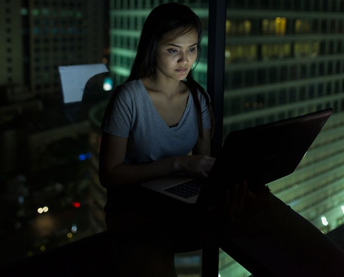 Analista trabajando de noche frente a un portátil